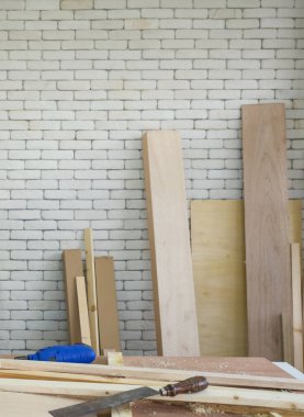 Öğle arası freninde mavi elektrikli matkap bir kenara bırakılmış. El aletleri ve odun yığınlarıyla dolu bir masa. Atölyede çalışma ortamı.