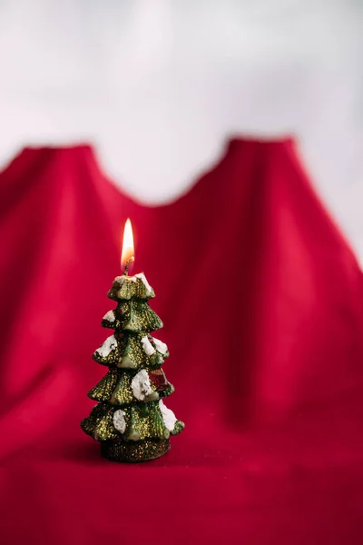 Свеча из новогодней елки горит на красном белом фоне. — стоковое фото