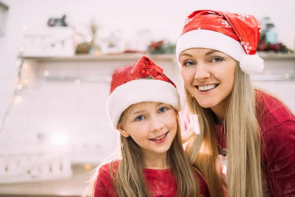 Young mom and teenage daughter girl in the kitchen are cooking with flour