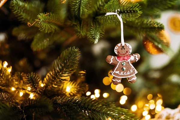 En pepparkaka i form av en man väger på en julgran med bokeh ljus dekoration. — Stockfoto