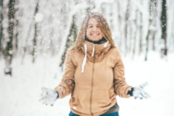 Capa de foto borrada para texto. Uma menina feliz se alegra na neve que voa na floresta. — Fotografia de Stock