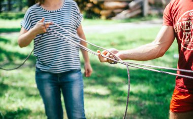 İş arkadaşları halatın düğümlerini çözerek takım oluşturma egzersizi yapıyor.