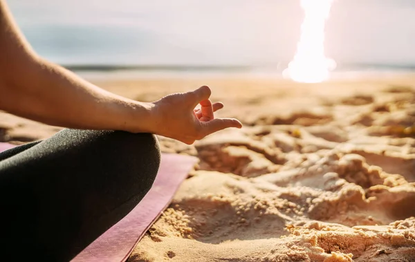 Yoga background. The girl sits on the beach by the sea in the lotus position. Side view. No face, hands, feet, sand. Meditation, balance, life balance, pacification, relaxation. High quality photo