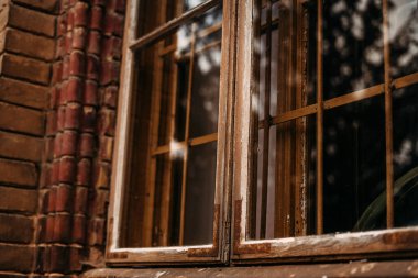 Ağaçların ve güneşin yansıması olan eski bir tuğla binanın penceresinin fotoğrafı