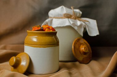 Kahverengi arka planda geleneksel seramik kavanozda ev yapımı çiğ mango turşusu.