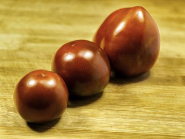 Kırsal ahşap arka planda Kumato domatesleri. 'Kumato', 'Olmeka' olarak bilinen koyu domateslerden oluşan bir tarladır.