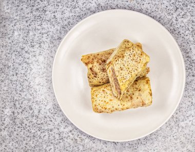 Mermer tezgahtaki beyaz tabakta etle doldurulmuş gözleme..