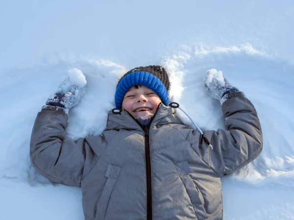 Glimlachende Blanke Jongen Groen Jasje Blauwe Muts Ligt Sneeuw — Stockfoto