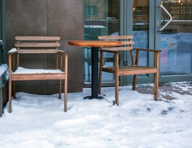 Kışın bir sokak kafesinin masa ve sandalyeleri karla kaplıdır..