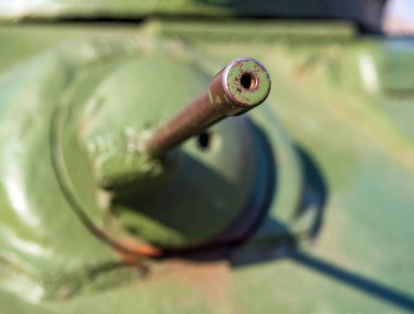 Yeşil tank gövdesinin arka planında makineli tüfek var. Yakın plan. Bulanık arkaplan.