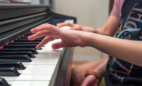 Piano private lesson. Master teaches a child to play piano. Young woman is teaching a kid to play the piano. Playing together. Concept of the music study and arts. Close-up. No faces.