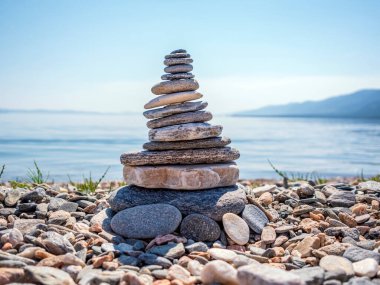Yaz güneşli bir günde Baykal Gölü kıyısında istiflenmiş taş piramidi. Yakın plan. Zen uyumu kavramı.