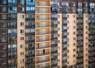 Binanın ön cephesinde çok sayıda pencere ve balkon var. Apartman bloğu. Konut binası.