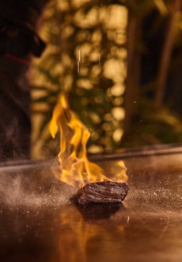 Japon şef, Teppanyaki usulü dilimlenmiş Kobe bifteği veya Wagyu bifteği pişiriyor. Sıcak ve lezzetli biftek, fesa, ranichi