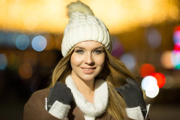 Vacker flicka, på kvällen, mot bakgrund av ljus, en vit hatt och en beige rock. leende framför kameran — Stockfoto