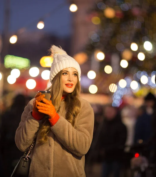 コーヒーと光の背景にある美しい女の子通り休日新年 夜の街を歩くと笑顔になり — ストック写真