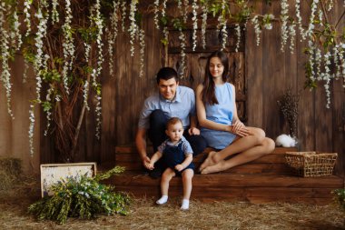 Köydeki aile, kollarında tavşanlarla. Anne ve babasının yanında küçük bir çocuk. Beyaz tavşanlar