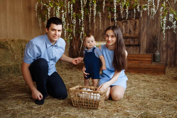 family in the village, with rabbits in their arms. little boy with mom and dad. white rabbits