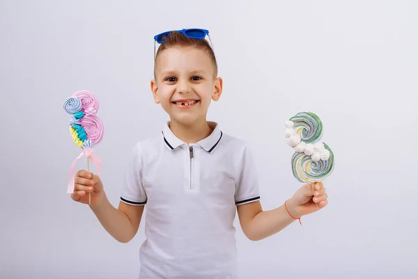 A boy in sunglasses on a white background holds a figure eight candy. Womens day, congratulations. men congratulate. March 8 Stock Photo