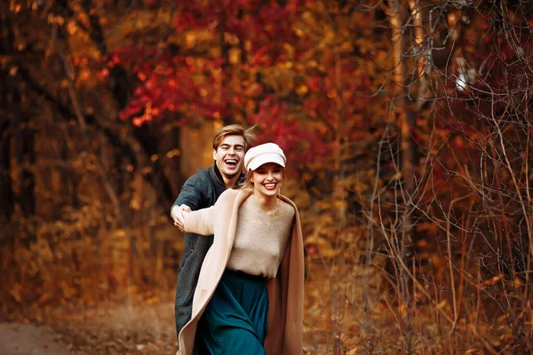 Coppia innamorata ride e cammina in autunno nel parco, nella foresta, foglie gialle. incontro e data. primo amore. Foto Stock Royalty Free
