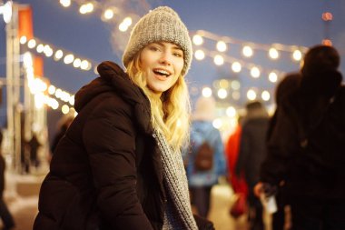 Kış şapkalı güzel bir kız Noel ağacının yanında, kış tatilleri, tatiller ve bir film fotoğrafının altında buğdayla yürüyor.