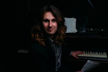 adamın yanında siyah bir piyano notlar görünüyor