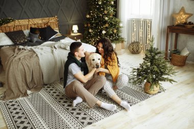 Mutlu çift kanepede köpekle oturuyor, Noel 'de. Evde yeni yıl. aile ve tarih