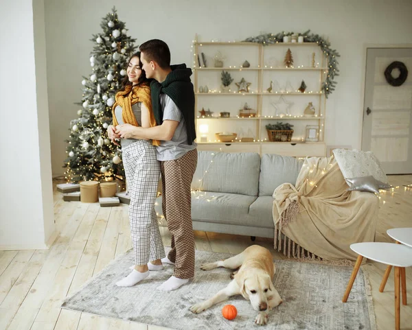 Casal feliz está sentado no sofá com o cão, Natal. Ano Novo em casa. família e data — Fotografia de Stock