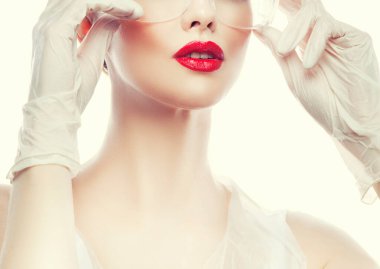 Kırmızı dudaklar. Güzellik uzmanı kadının çekici bir fotoğrafı. Doktor üniforması giyiyor.