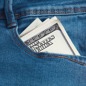 Dolarové bankovky v kapse modrých džín.