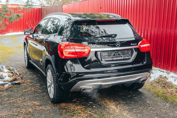 MOSCOW, RUSSIA-NOVEMBER 26, 2020: Black Mercedes Benz GLA 250, 가을 배경에 배기관에서 나오는 연기, 후방 뷰. 스톡 이미지