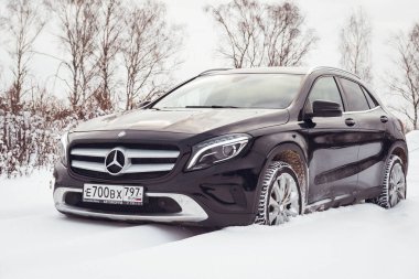 MOSCOW, RUSSIA-JANUARY 10, 2021: Bir siyah Mercedes Benz GLA 250 lüks geçidi karlı bir kış ormanında kar yığınlarının içinden geçiyor. Yüksek kalite fotoğraf