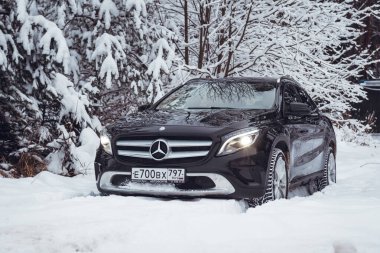 MOSCOW, RUSSIA-JANUARY 10, 2021: Bir siyah Mercedes Benz GLA 250 lüks geçidi karlı bir kış ormanında kar yığınlarının içinden geçiyor. Yüksek kalite fotoğraf