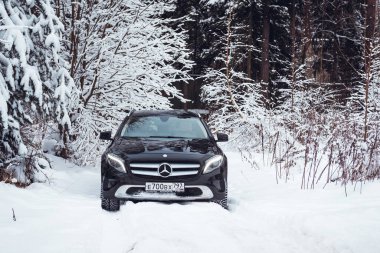MOSCOW, RUSSIA-JANUARY 10, 2021: Bir siyah Mercedes Benz GLA 250 lüks geçidi karlı bir kış ormanında kar yığınlarının içinden geçiyor. Yüksek kalite fotoğraf