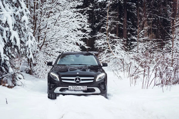 MOSCOW, RUSSIA-JANUARY 10, 2021: Bir siyah Mercedes Benz GLA 250 lüks geçidi karlı bir kış ormanında kar yığınlarının içinden geçiyor. Yüksek kalite fotoğraf