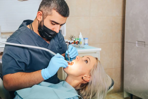 İşlem sırasında ağzı açık bir şekilde dişçi koltuğundaki bir erkek dişçinin resepsiyonundaki bir kız..