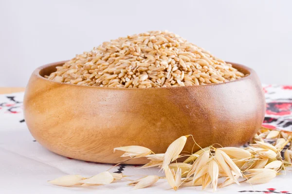 在一个木碗和耳朵的在桌上的玉米燕麦燕麦 — 图库照片