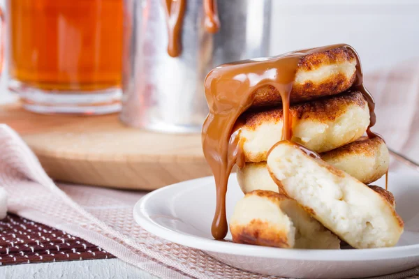 Cheesecakes with condensed milk and two cups of tea — Stock Photo, Image