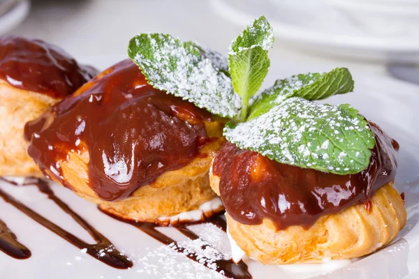 Profiteroles con salsa de chocolate y hoja de menta — Foto de Stock