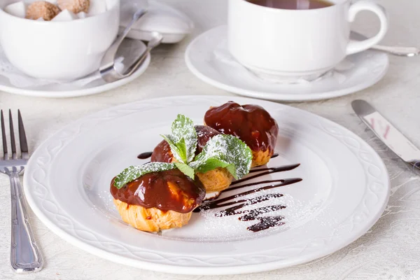 Profiteroles with chocolate sauce and mint leaf — Stock Photo, Image