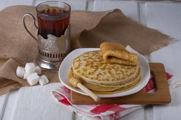 Traditionele Russische maaltijd - pannenkoeken met honing en zoete thee — Stockfoto