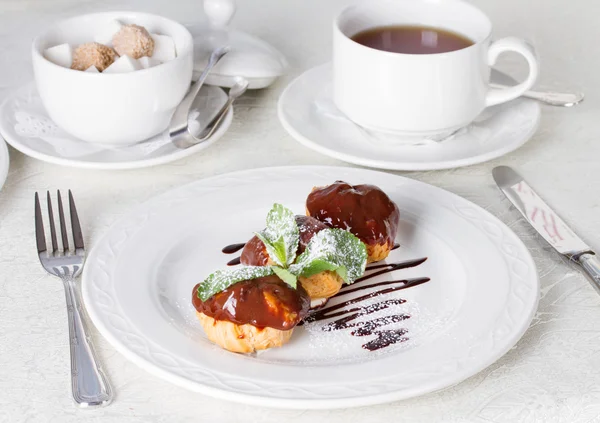 Profiteroles con salsa de chocolate y hoja de menta — Foto de Stock