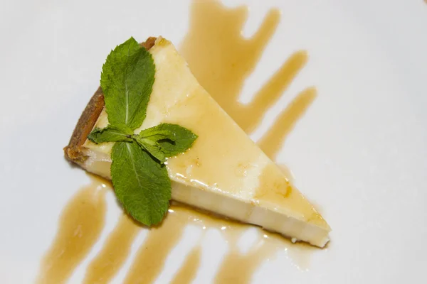 Tarta de queso con jarabe de caramelo una hoja de menta — Foto de Stock