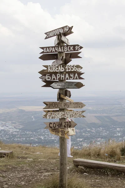 Indicadores de distancias a diferentes ciudades y turistas en la cima del Monte Mashuk —  Fotos de Stock