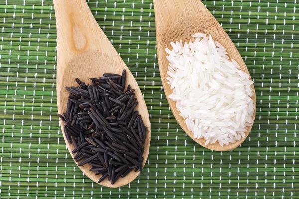 Two wooden spoons with black and white rice — Stock Photo, Image