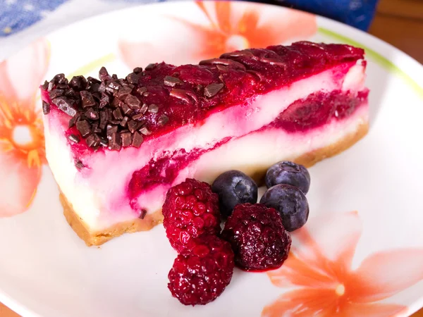Pedaço de cheesecake em um prato colorido com bagas frescas — Fotografia de Stock