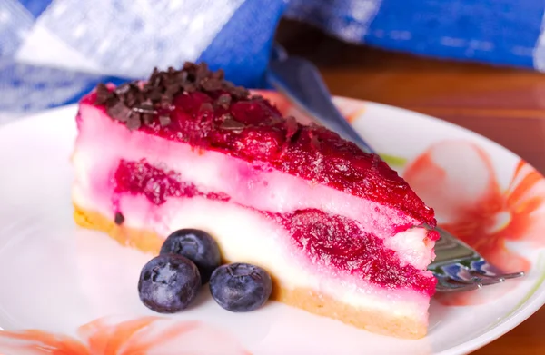 Κομμάτι cheesecake σε ένα πολύχρωμο πιάτο με φρέσκα μούρα — Φωτογραφία Αρχείου