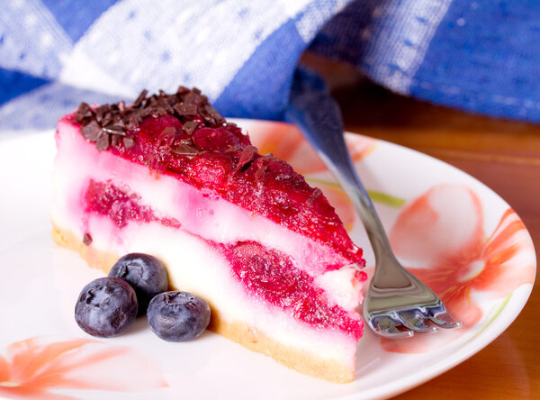 Piece of cheesecake on a colorful dish with fresh berries