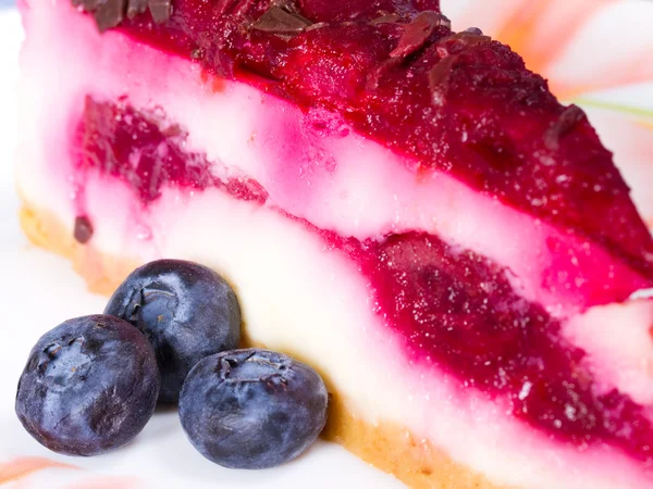Κομμάτι cheesecake σε ένα πολύχρωμο πιάτο με φρέσκα μούρα — Φωτογραφία Αρχείου