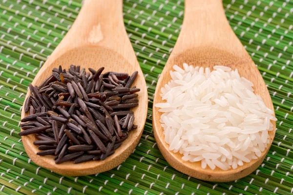 Two wooden spoons with black and white rice — Stock Photo, Image